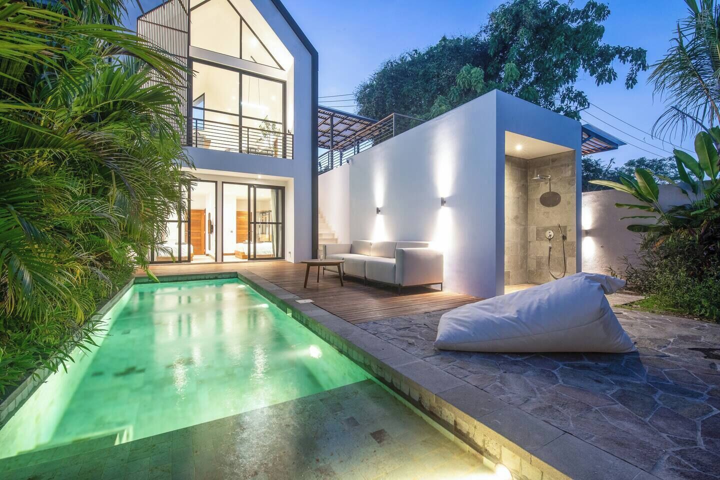 Ein modernes Haus mit Swimmingpool, einer Terrasse mit Gartenmöbeln und einem separaten Gebäude mit Dusche.