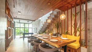 A modern dining area with a long wooden table, multiple chairs, and hanging pendant lights. - Robyn s Villa New Modern 4 BR Villa Canggu (Kerobokan)