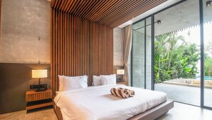 A modern bedroom with a large bed, wooden slatted headboard, and a view of a lush garden through large sliding glass doors. - Robyn s Villa New Modern 4 BR Villa Canggu (Kerobokan)