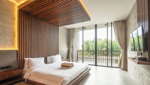 A modern bedroom with a large bed, a TV, and a balcony with a view of greenery. - Robyn s Villa New Modern 4 BR Villa Canggu (Kerobokan)