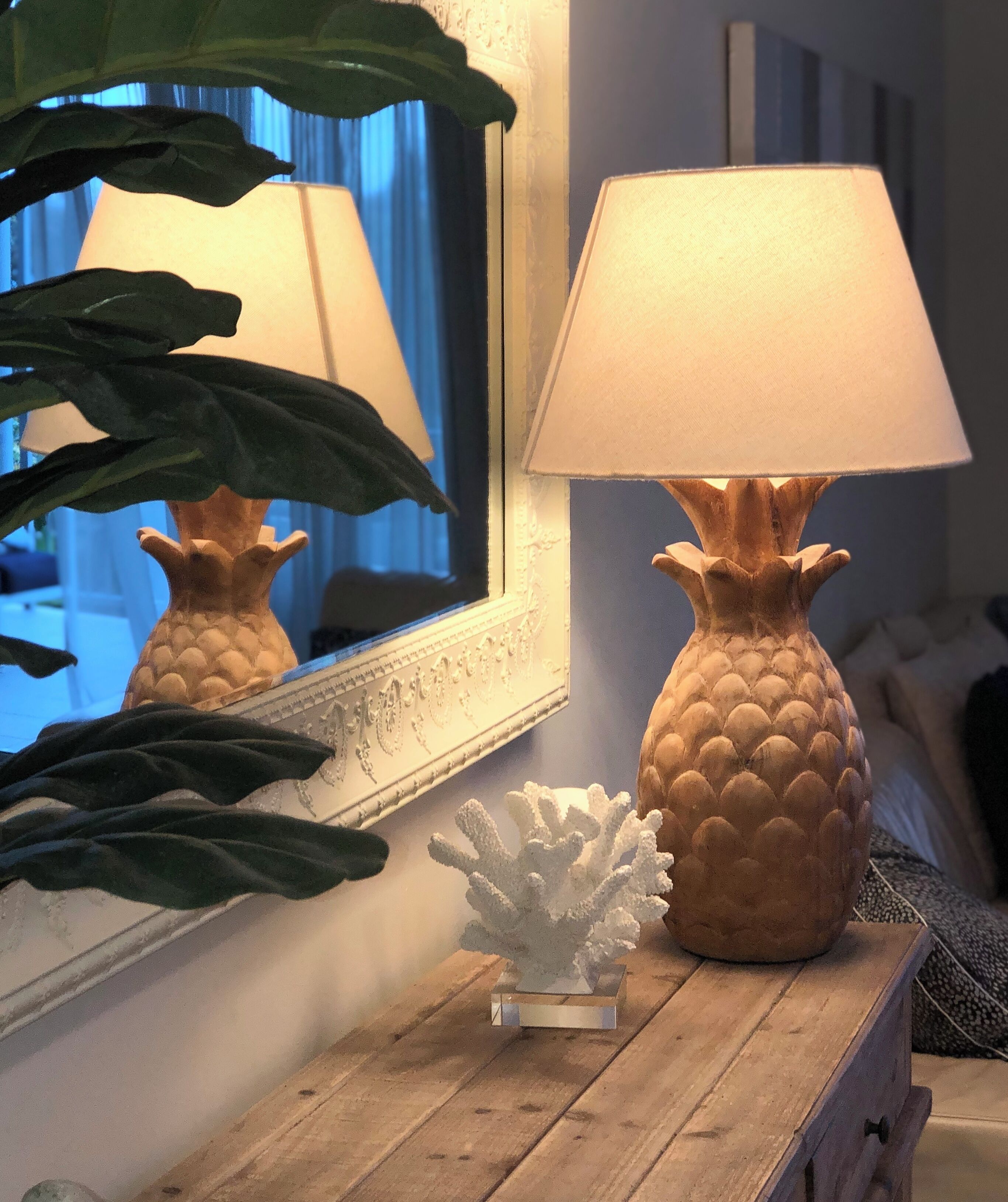A wooden table with a pineapple-shaped lamp and a coral sculpture.