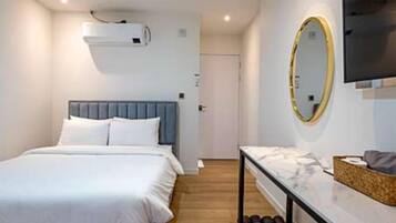 A bedroom with a bed, a bedside table, a mirror, and an air conditioning unit.