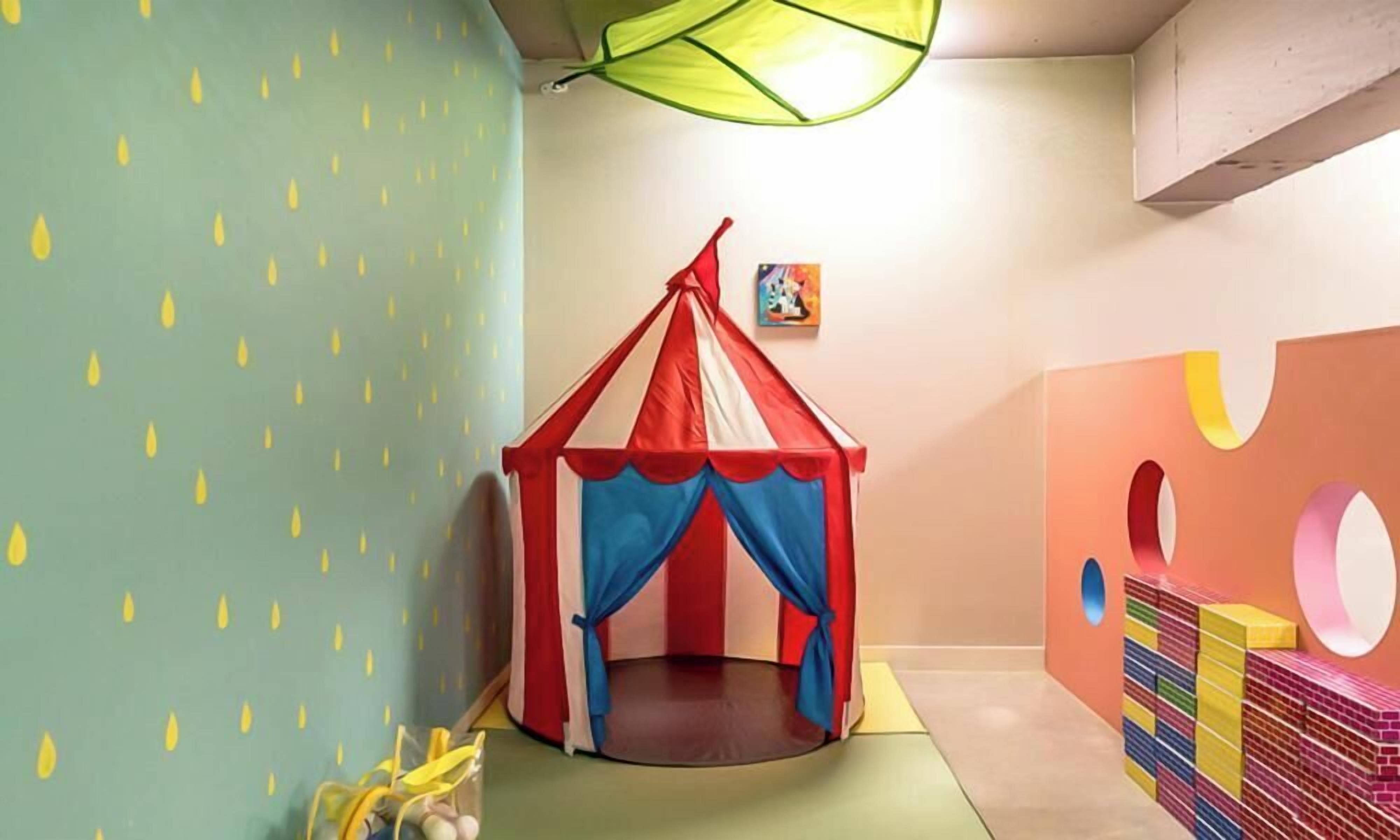 A play area with a tent, colorful walls, and a stack of building blocks.