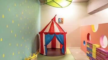 A play area with a tent, colorful walls, and a stack of building blocks.