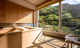 Cozinha moderna com armários de madeira e uma grande janela com vista para uma área arborizada.