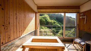 A wooden cabin with a large window offering a view of a forested area.