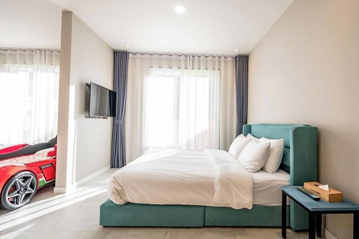 A hotel room with a bed, a TV mounted on the wall, and a window with curtains.