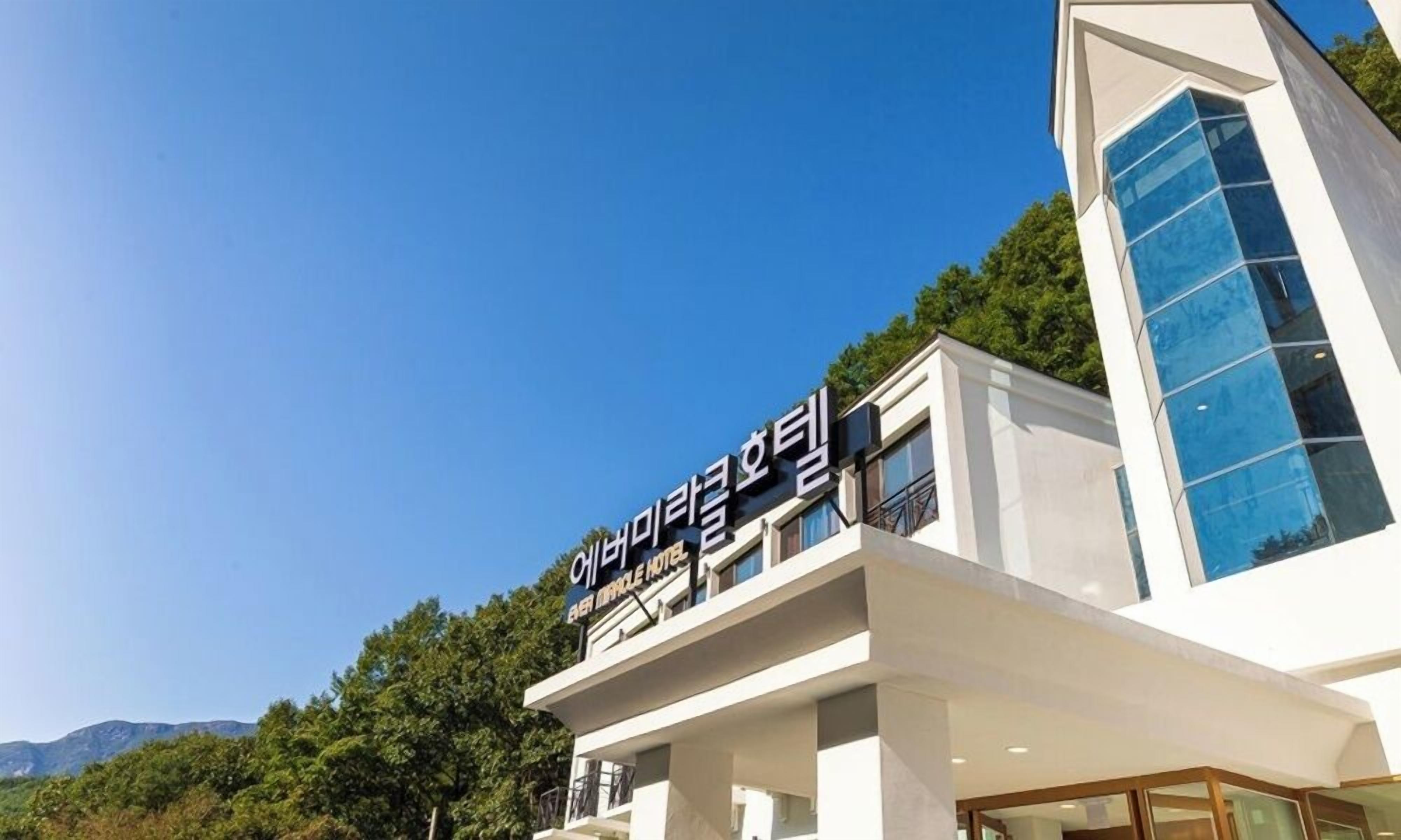 Un hotel moderno con un cielo despejado y vegetación al fondo.
