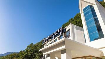 Un hotel moderno con un cielo despejado y vegetación al fondo.