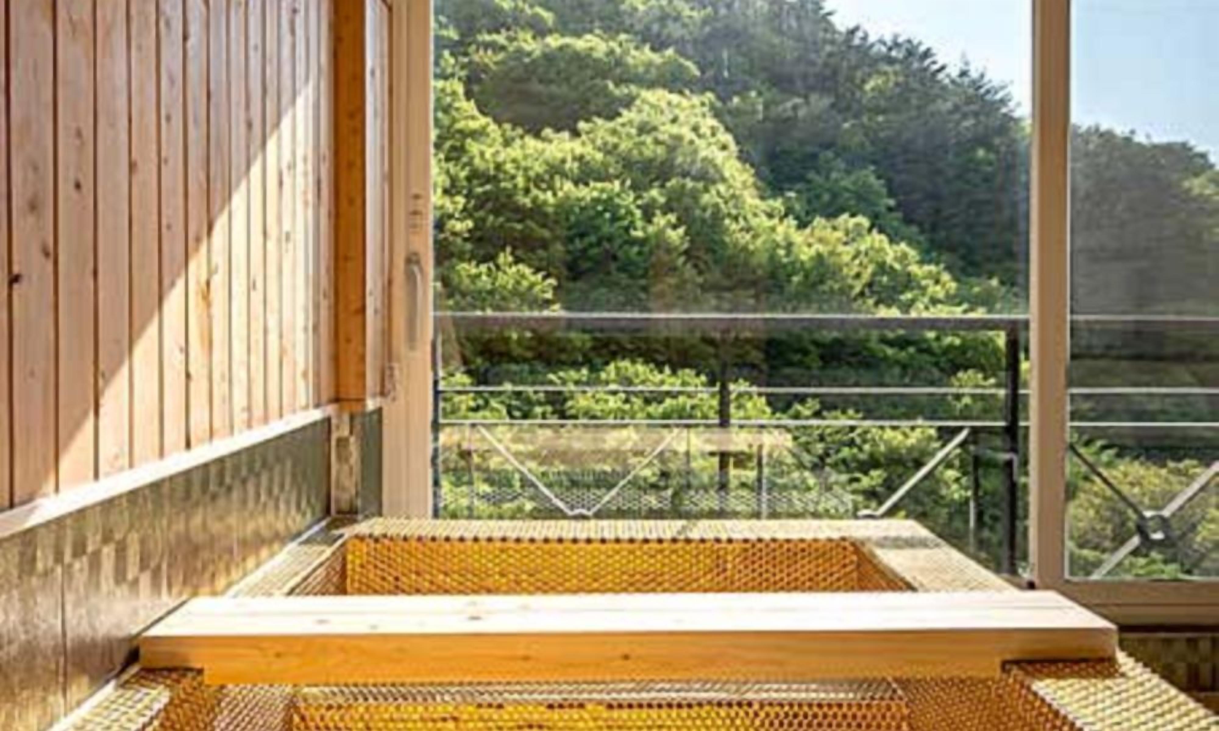 A wooden cabin with a large window overlooking a forested area.
