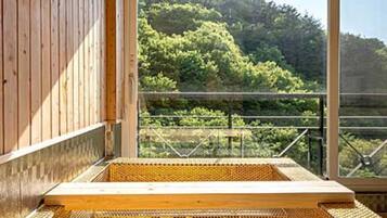 A wooden cabin with a large window overlooking a forested area.