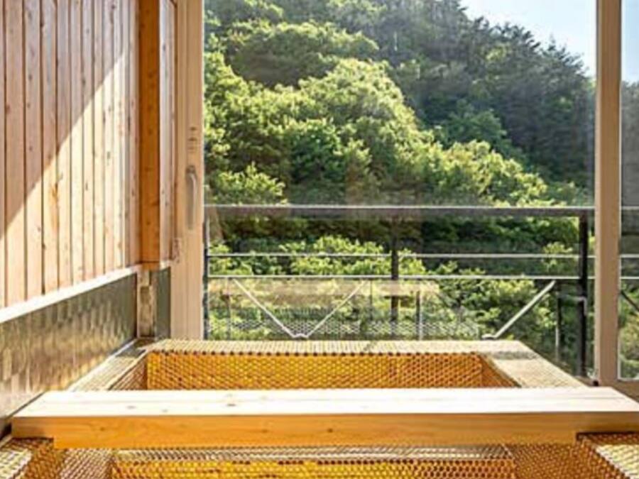 A wooden cabin with a large window overlooking a forested area.