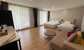 Quarto de hotel moderno com duas camas, um sofá, uma mesa de centro e uma televisão.