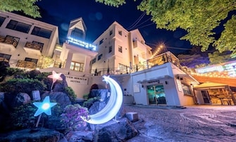 Entrada de hotel com uma placa indicando "Ever Miracle Hotel", uma decoração de luz em formato de estrela e uma luz em formato de crescente.