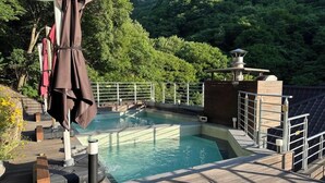 A hot spring area with a wooden deck, a pool, and a metal railing. - Miryang EVERMIRACLE HOTEL (Miryang)