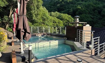 Área de fontes termais com um deck de madeira, piscina e guarda-corpo de metal.