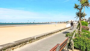 A coastal promenade with a sandy beach, a paved walkway, and a palm tree. - Chalet moderne La Baule-Guérande by Interhome (Guérande)