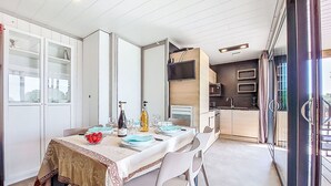 A compact living space with a dining area, kitchenette, and a sliding glass door leading to an outdoor area. - Chalet moderne La Baule-Guérande by Interhome (Guérande)