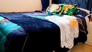 A bed with a black headboard, colorful pillows, and a dark blue bedspread.