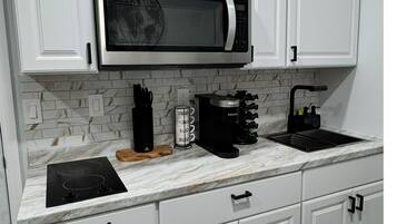 A modern kitchen with white cabinets, a built-in microwave, a coffee maker, and a gas stove.