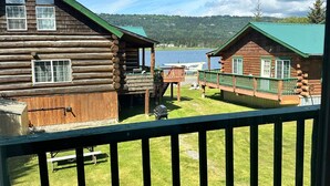 A log cabin hotel with a deck and a view of a lake. - Chenik Cabin, Homer Floatplane Lodge (Homer)