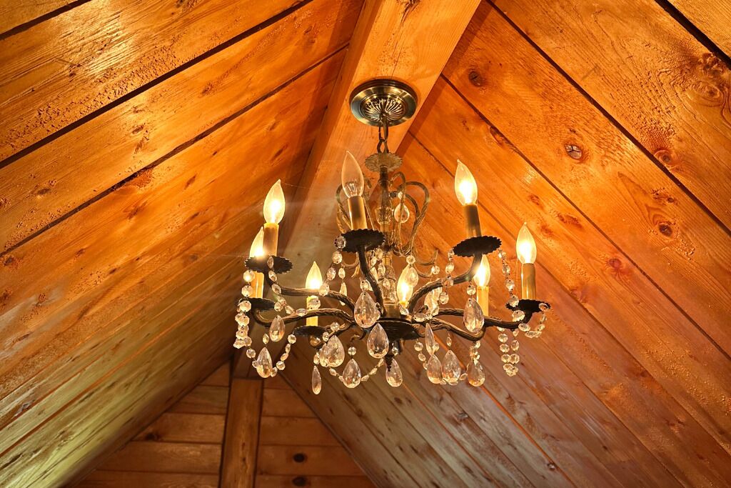 A chandelier with multiple candle-like lights hanging from a wooden ceiling.