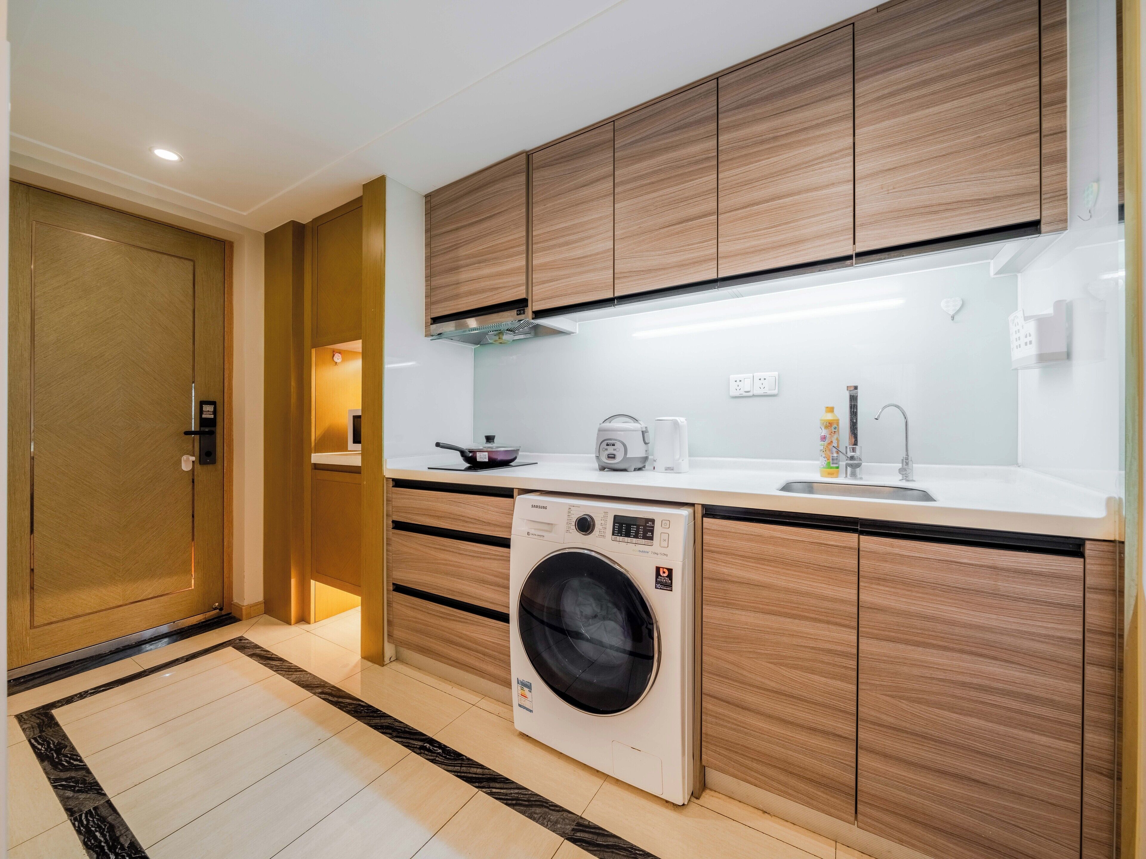 A modern kitchen with wooden cabinets, a built-in washing machine, a sink, and a stove.