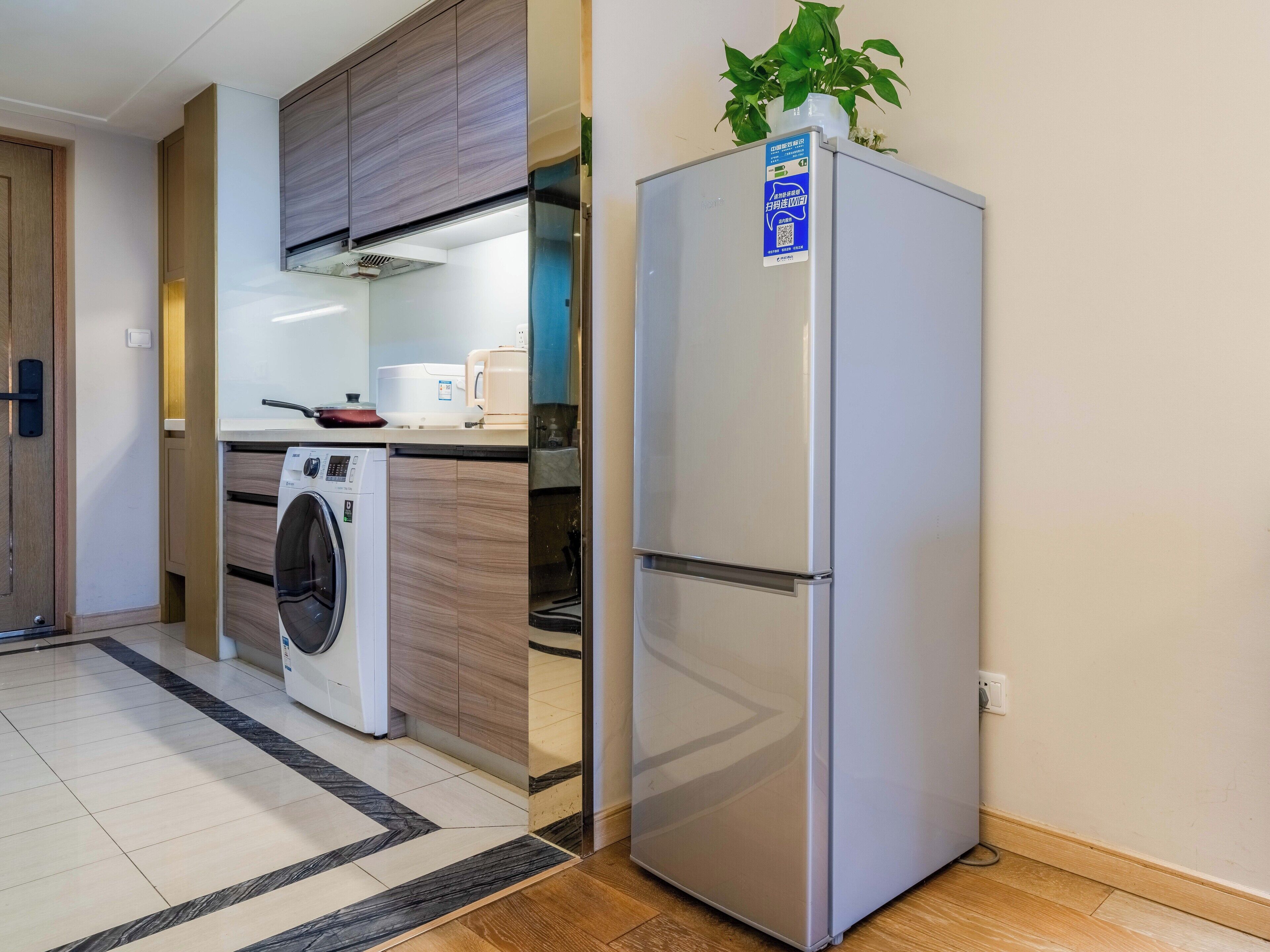 A compact kitchen with a washing machine, a refrigerator, and a microwave.
