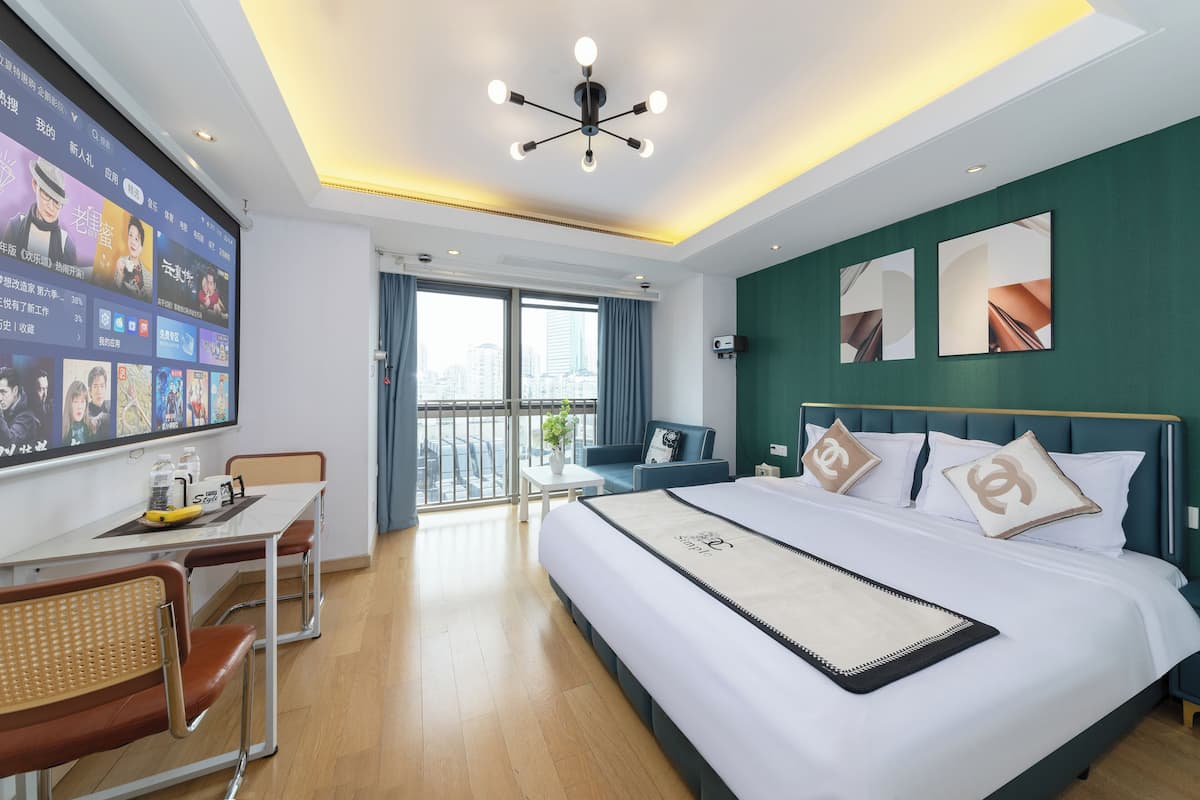 Une chambre d’hôtel moderne dotée d’un grand lit, d’un bureau avec un ordinateur, d’une chaise et offrant une vue sur la ville par la fenêtre.