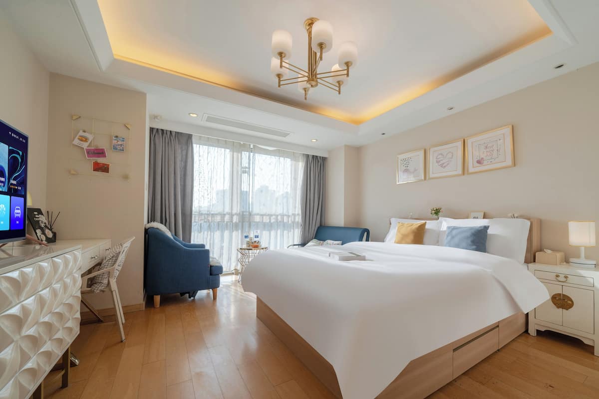 Une chambre d’hôtel avec un grand lit, un bureau avec un ordinateur, une chaise et une table de chevet avec une lampe.