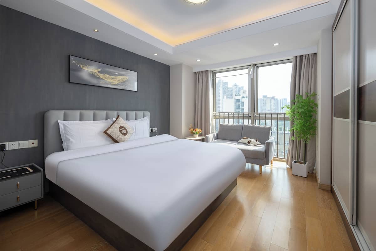 Une chambre d’hôtel moderne dotée d’un grand lit, d’un coin salon et offrant une vue sur la ville.