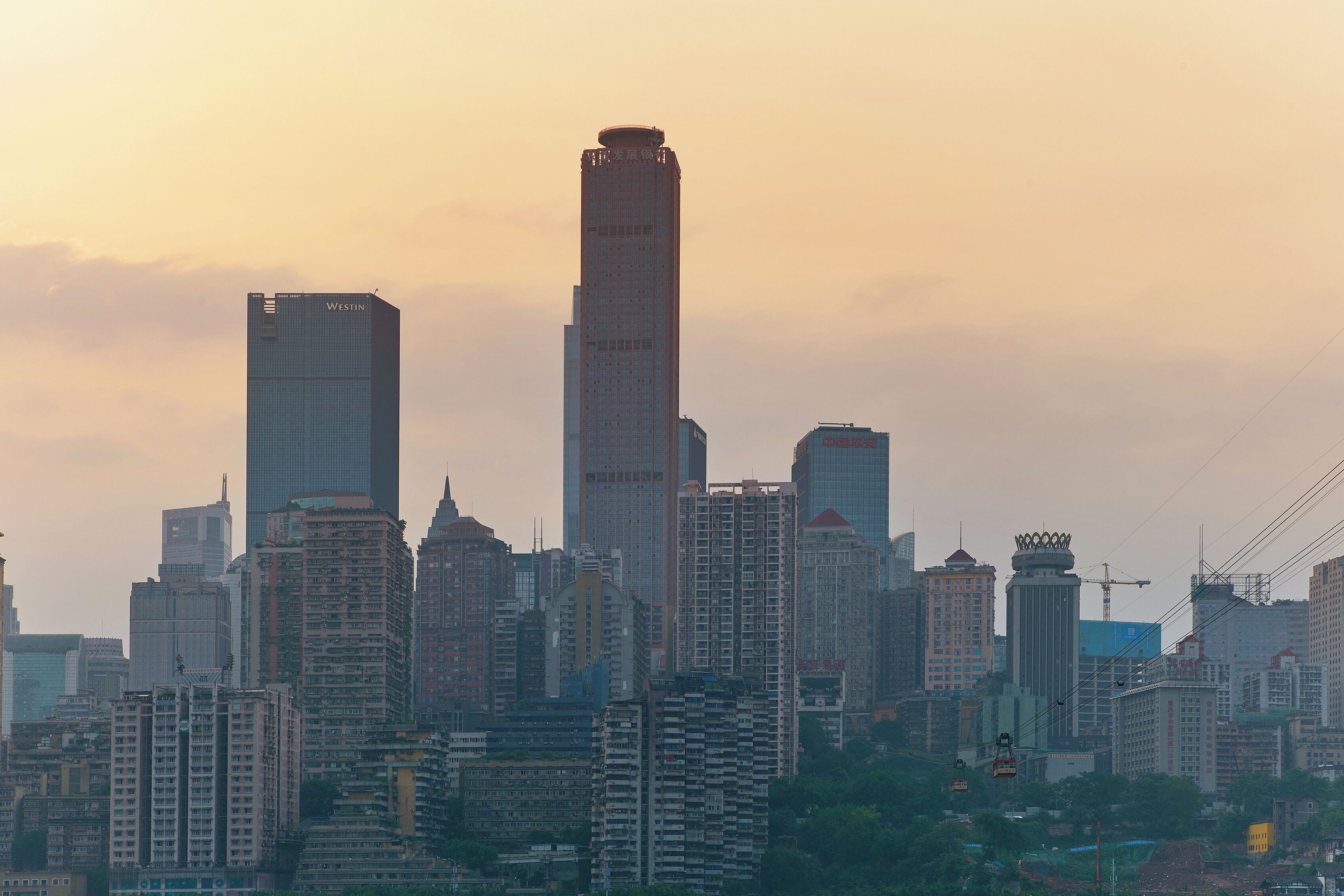 A city skyline with multiple high-rise buildings, including a prominent skyscraper with a unique top design.