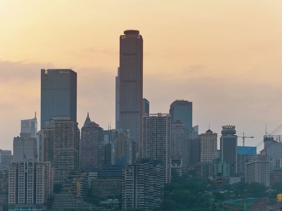 A city skyline with multiple high-rise buildings, including a prominent skyscraper with a unique top design.