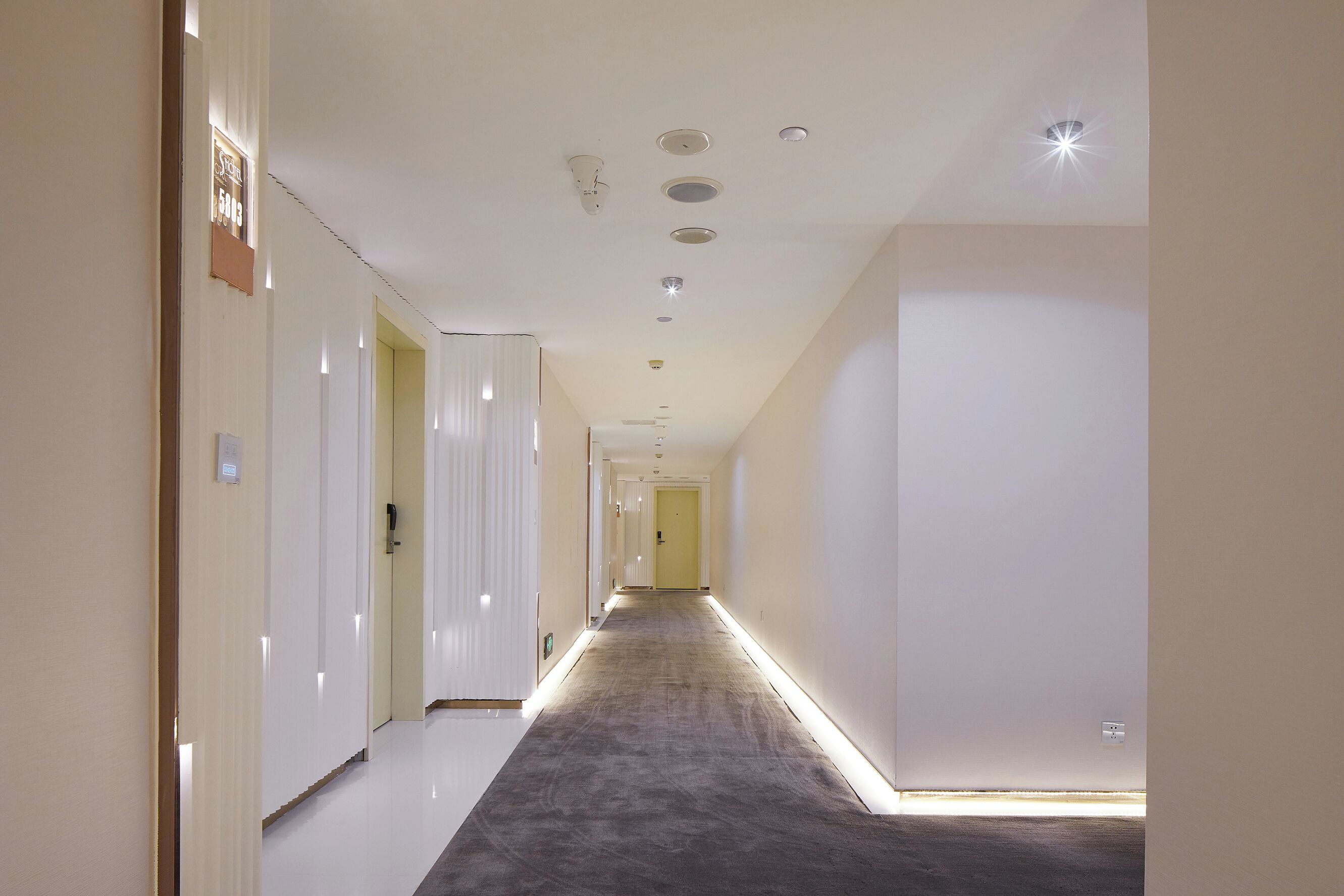 Un pasillo largo y estrecho con suelo alfombrado e iluminación empotrada.