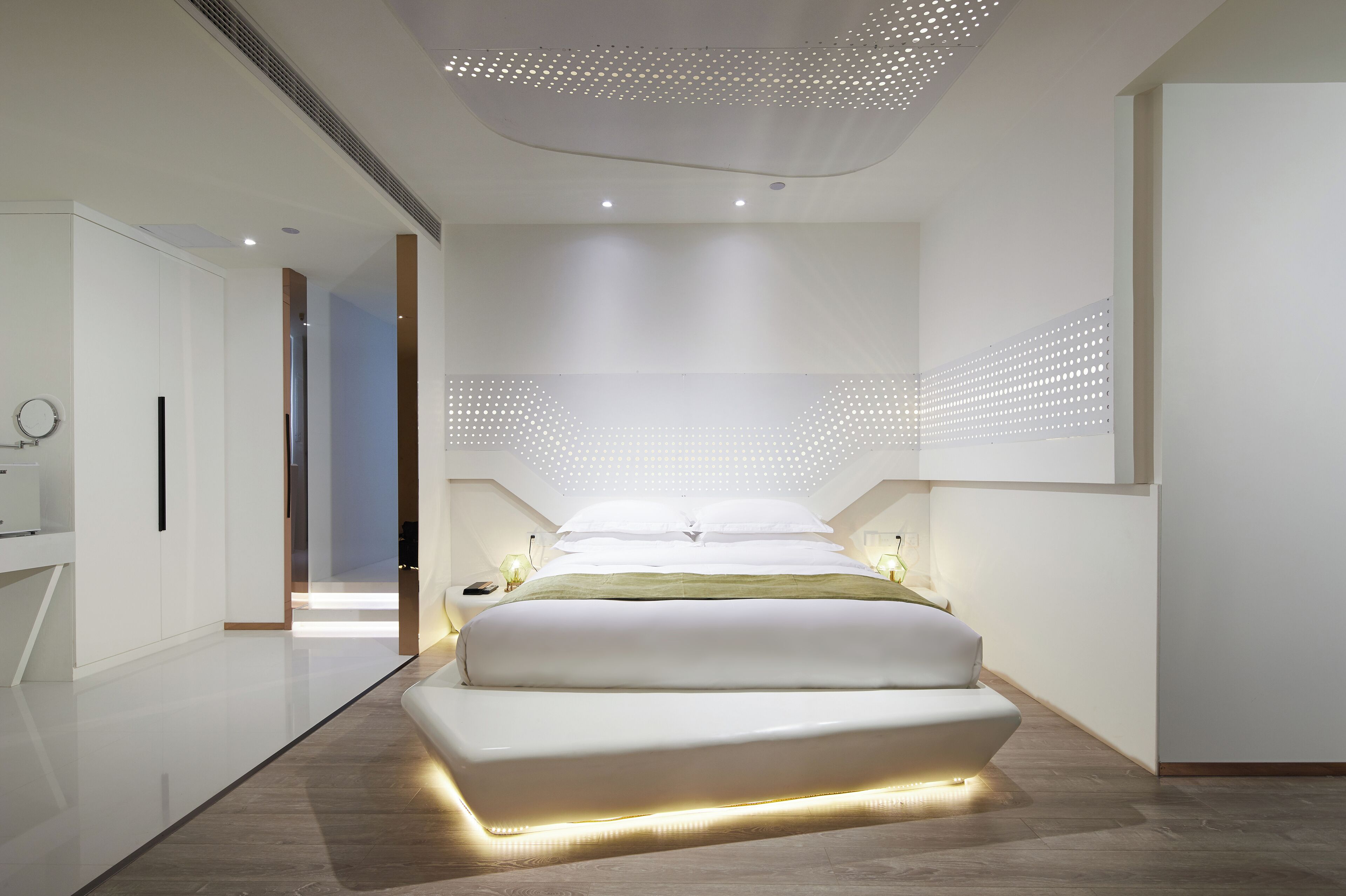 Ein modernes Schlafzimmer mit einem großen Bett, einem begehbaren Kleiderschrank und einer Decke mit einem durchbrochenen Design.