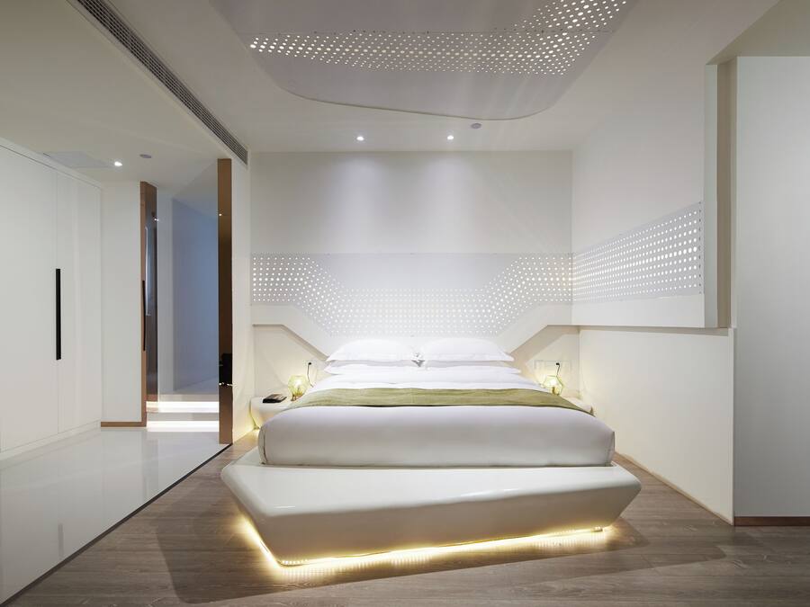 Ein modernes Schlafzimmer mit einem großen Bett, einem begehbaren Kleiderschrank und einer Decke mit einem durchbrochenen Design.