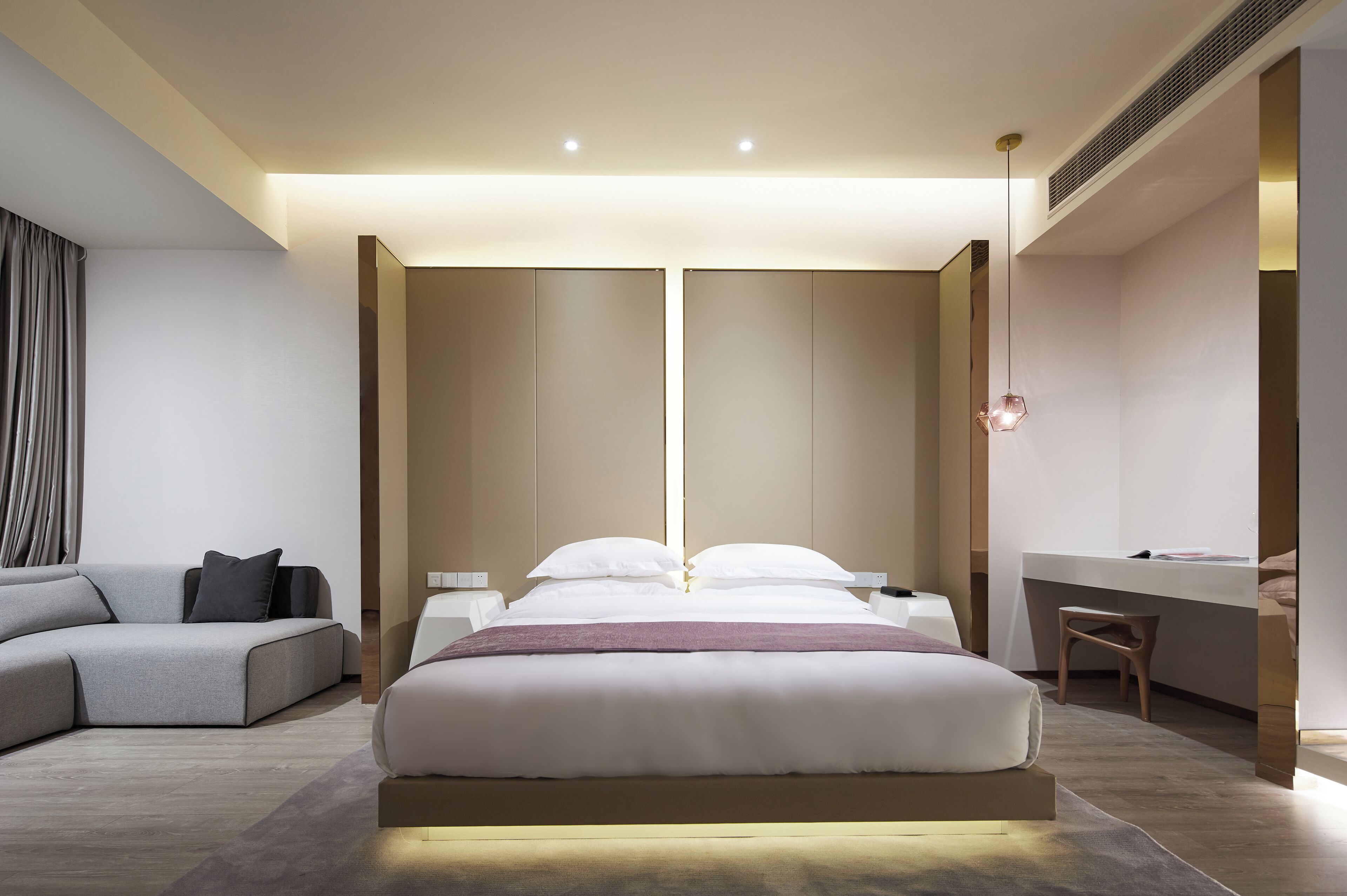 A modern bedroom with a large bed, a desk, and a sofa.