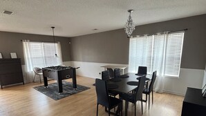 Tilava olohuone, jossa on ruokailutila, takka ja koristeellinen kattokruunu.