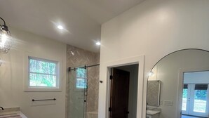 Une salle de bain moderne avec une douche à parois de verre, un grand miroir et un meuble-lavabo.