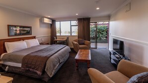 Een hotelkamer met een bed, een bank, een televisie, een tafel en een stoel.