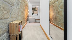 Un couloir étroit aux murs de pierre, avec un banc en bois et un canapé au fond.