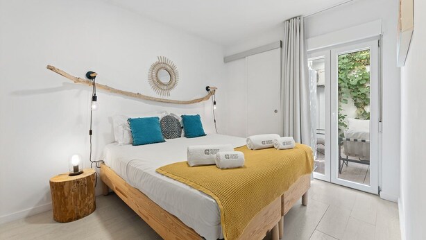 Une chambre moderne avec un lit en bois, des murs blancs et une vue sur la verdure.