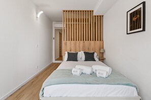 Een hotelkamer met een bed, een houten hoofdbord, een nachtkastje en een ingelijste foto aan de muur.