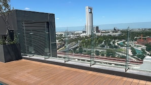 Ein Pool auf dem Dach mit Blick auf die Stadt, darunter ein hohes Gebäude und eine Brücke.