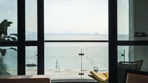A view from a room with large windows overlooking a beach, featuring a lifeguard stand and a distant island.