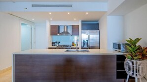 Una cocina moderna con una isla central, electrodomésticos de acero inoxidable y una pared de acento blanca.