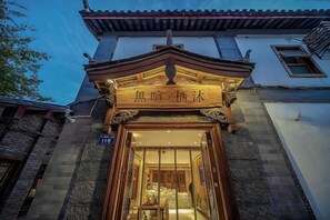A traditional building with a wooden entrance and a sign above it. - UNThinkHotel Qimu inn (Lijiang)