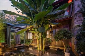A traditional Japanese-style building with a covered outdoor area, stone steps, and a water feature. - UNThinkHotel Qimu inn (Lijiang)