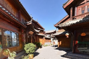 A traditional wooden building with a courtyard, large windows, and hanging lanterns.