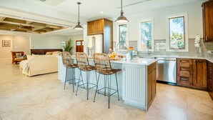 A spacious kitchen with a central island, bar stools, and a large refrigerator. - Villa La Colina - Tierra Del Sol Mansion 3 minutes to BEACH, 4 BDRM 4.5 BTHRM (Tierra Del Sol)
